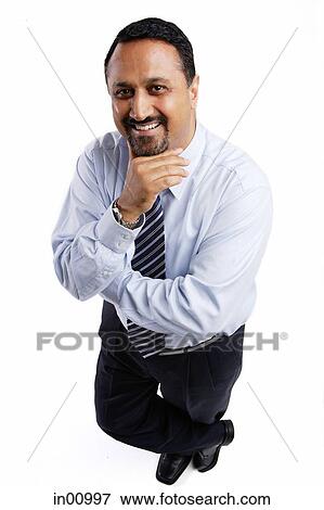 Businessman looking up at camera, arms crossed, hand on chin View Large Photo Image Stock Photo - Businessman looking up at camera, arms crossed, hand on chin. Fotosearch