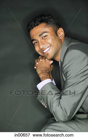 Businessman resting head on hands, smiling at camera View Large Photo Image Stock Photo - Businessman resting head on hands, smiling at camera. Fotosearch