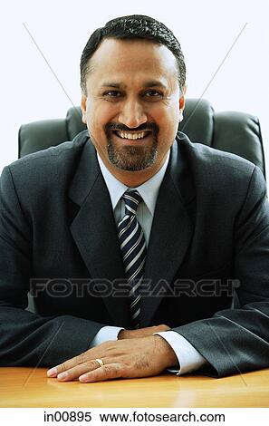 Stock Photography - Businessman sitting, looking at camera, portrait. Fotosearch
