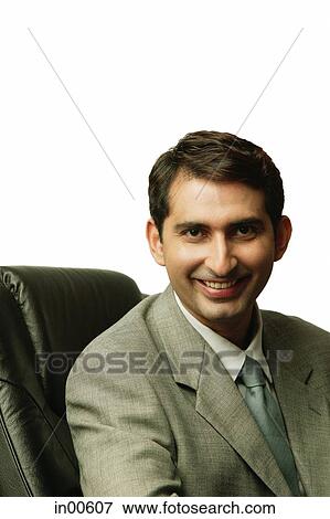 Businessman sitting on chair, looking at camera View Large Photo Image Stock Photo - Businessman sitting on chair, looking at camera. Fotosearch