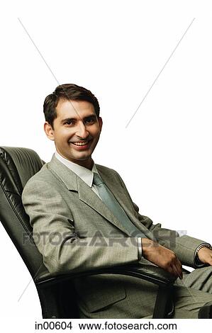 Picture - Businessman sitting on chair, smiling at camera. Fotosearch