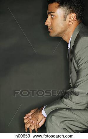 Businessman sitting, side view, hands clasped View Large Photo Image Stock Photo - Businessman sitting, side view, hands clasped. Fotosearch