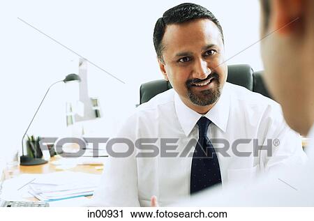 Stock Image - Businessman smiling at person in front of him. Fotosearch