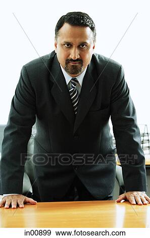 Businessman standing at desk, hands on table, looking at camera View Large Photo Image Stock Photo - Businessman standing at desk, hands on table, looking at camera. Fotosearch