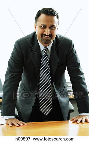 Businessman standing at desk View Large Photo Image Stock Photo - Businessman standing at desk. Fotosearch