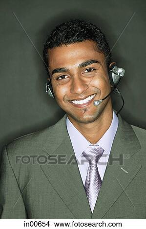 Picture - Businessman using headset, looking at camera. Fotosearch