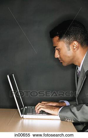 Businessman using laptop, side view View Large Photo Image Stock Photography - Businessman using laptop, side view. Fotosearch