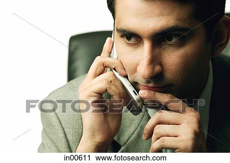 Stock Image - Businessman using mobile phone, looking away. Fotosearch