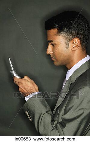 Businessman using mobile phone, side view View Large Photo Image Stock Image - Businessman using mobile phone, side view. Fotosearch