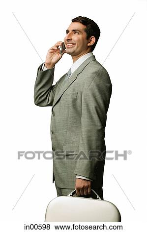 Stock Photo - Businessman using mobile phone, carrying briefcase, smiling. Fotosearch
