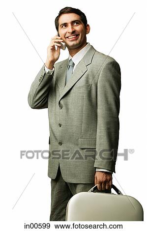 Stock Photo - Businessman using mobile phone, carrying briefcase, looking away. Fotosearch
