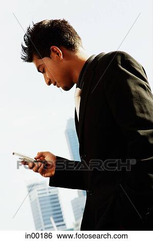 Stock Photograph - Businessman using mobile phone, text messaging. Fotosearch