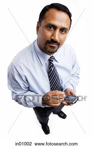Stock Image - Businessman using PDA, looking at camera. Fotosearch