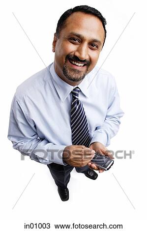 Stock Image - Businessman using PDA, smiling at camera. Fotosearch