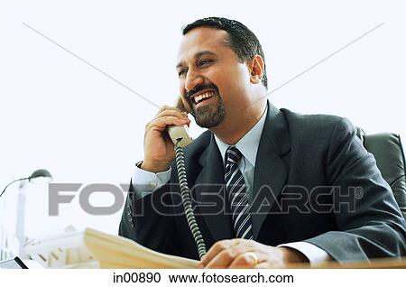 Businessman using telephone in office, smiling View Large Photo Image Stock Image - Businessman using telephone in office, smiling. Fotosearch