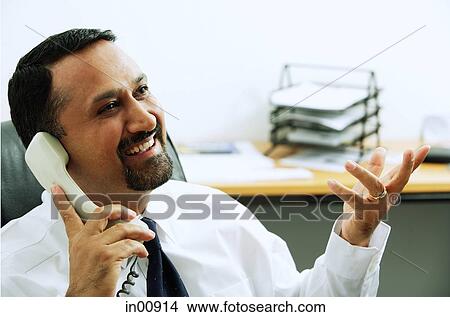 Businessman using telephone, looking away, hand raised View Large Photo Image Picture - Businessman using telephone, looking away, hand raised. Fotosearch