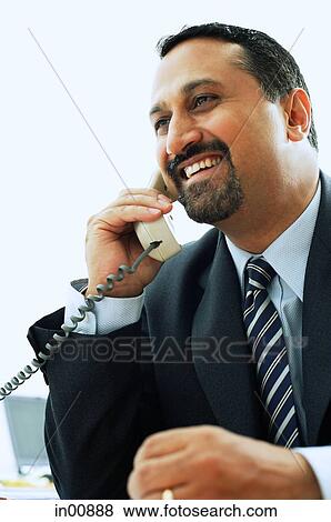 Stock Photo - Businessman using telephone, smiling. Fotosearch