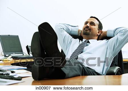 Businessman with feet on desk, hands behind head View Large Photo Image Stock Photo - Businessman with feet on desk, hands behind head. Fotosearch