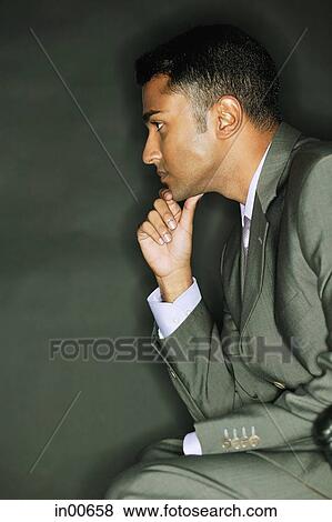 Stock Photo - Businessman with hand on chin, looking away. Fotosearch