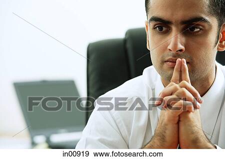 Businessman with hands clasped, fingers on mouth, looking away View Large Photo Image Stock Photo - Businessman with hands clasped, fingers on mouth, looking away. Fotosearch