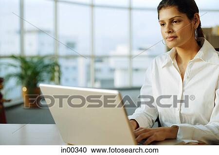 Stock Image - Businesswoman using laptop, portrait. Fotosearch