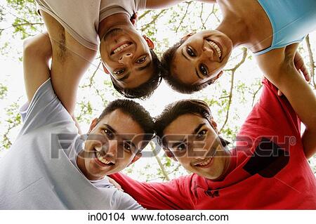 Picture - Circle of friends, arms around each other, looking down at camera. Fotosearch