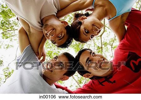 Stock Photograph - Circle of friends, arms around each other, looking at each other. Fotosearch