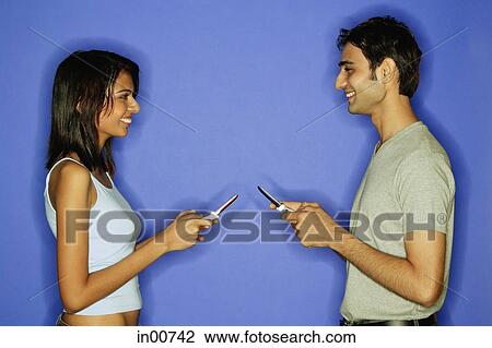 Couple face to face, holding mobile phones View Large Photo Image Stock Image - Couple face to face, holding mobile phones. Fotosearch