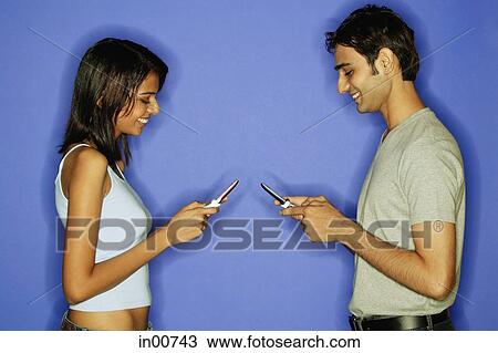 Couple face to face, holding mobile phones View Large Photo Image Stock Image - Couple face to face, holding mobile phones. Fotosearch