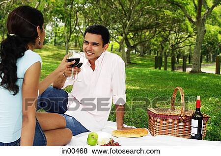 Couple having a picnic, toasting with wine glasses View Large Photo Image Stock Photo - Couple having a picnic, toasting with wine glasses. Fotosearch