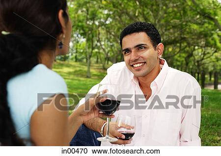 Couple holding wine glasses in park, over the shoulder view View Large Photo Image Stock Image - Couple holding wine glasses in park, over the shoulder view. Fotosearch