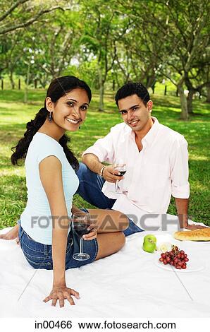 Couple holding wine glasses, sitting on picnic blanket View Large Photo Image Stock Photograph - Couple holding wine glasses, sitting on picnic blanket. Fotosearch