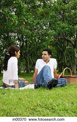 Couple in park, sitting on grass, picnic basket next to them View Large Photo Image Stock Image - Couple in park, sitting on grass, picnic basket next to them. Fotosearch