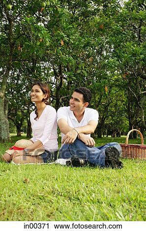Couple in park, sitting on grass, looking away View Large Photo Image Stock Image - Couple in park, sitting on grass, looking away. Fotosearch