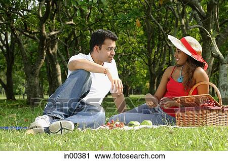 Couple in park, sitting on grass, having picnic View Large Photo Image Stock Image - Couple in park, sitting on grass, having picnic. Fotosearch