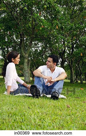Couple in park, sitting on grass View Large Photo Image Stock Photo - Couple in park, sitting on grass. Fotosearch
