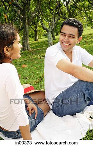 Couple in park, sitting on picnic blanket, looking at each other View Large Photo Image Stock Image - Couple in park, sitting on picnic blanket, looking at each other. Fotosearch