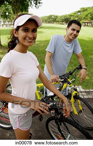 Stock Photo - Couple on bicycles, looking at camera. Fotosearch
