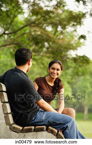 Couple sitting and talking on bench View Large Photo Image Stock Photo - Couple sitting and talking on bench. Fotosearch