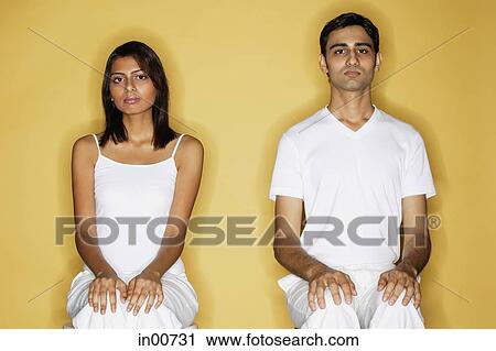 Stock Image - Couple sitting apart, facing forward. Fotosearch