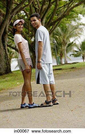 Couple standing side by side, looking over shoulder View Large Photo Image Stock Photo - Couple standing side by side, looking over shoulder. Fotosearch