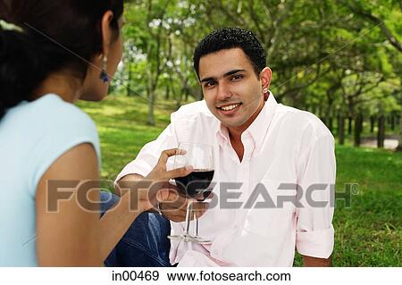Stock Photo - Couple toasting with wine glasses, man looking at camera. Fotosearch
