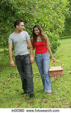Couple walking in park, arm in arm, woman carrying picnic basket View Large Photo Image Stock Image - Couple walking in park, arm in arm, woman carrying picnic basket. Fotosearch