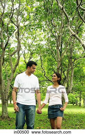Couple walking in park, holding hands, looking at each other View Large Photo Image Stock Image - Couple walking in park, holding hands, looking at each other. Fotosearch