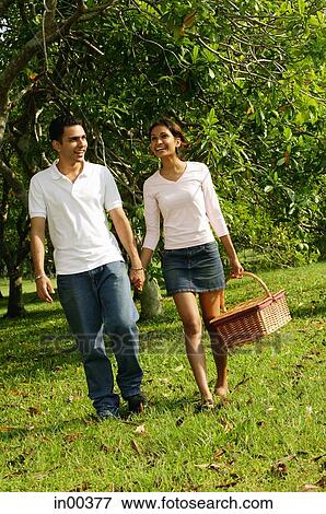 Couple walking in park, woman carrying picnic basket View Large Photo Image Stock Photo - Couple walking in park, woman carrying picnic basket. Fotosearch