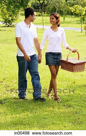 Couple walking in park, woman carrying picnic basket View Large Photo Image Stock Photo - Couple walking in park, woman carrying picnic basket. Fotosearch