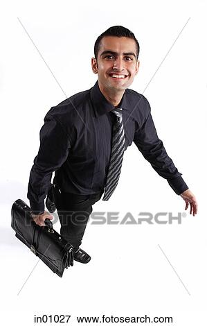 Stock Photo - Executive carrying briefcase, walking, looking up at camera. Fotosearch