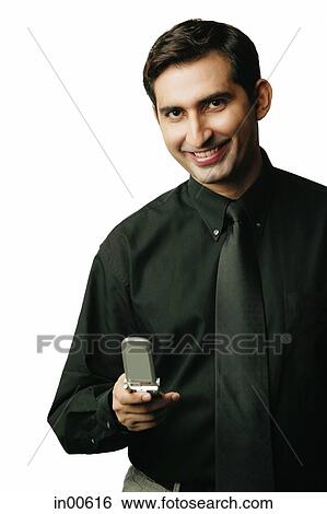 Executive holding mobile phone, smiling at camera View Large Photo Image Stock Photograph - Executive holding mobile phone, smiling at camera. Fotosearch