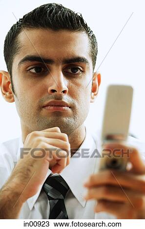 Stock Image - Executive looking at mobile phone, hand on chin. Fotosearch