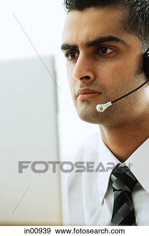 Executive using headset, using laptop View Large Photo Image Stock Photo - Executive using headset, using laptop. Fotosearch